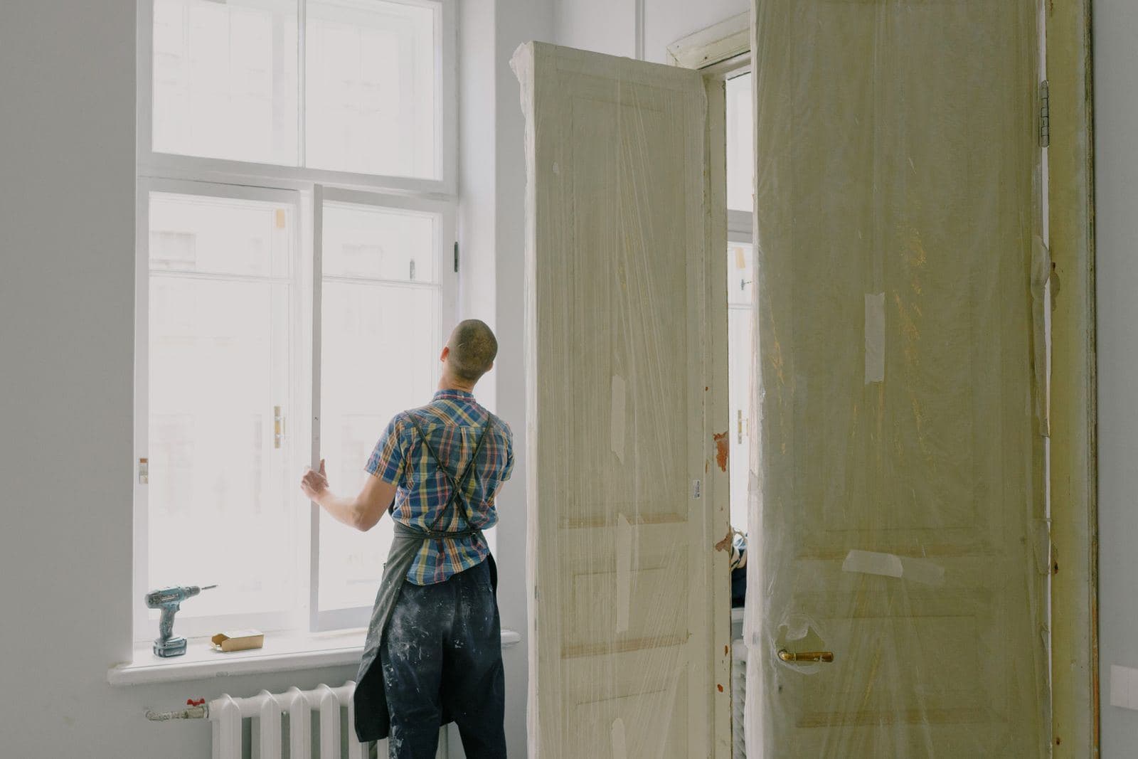 Handwerker arbeitet an einem Fenster in einem leeren Raum