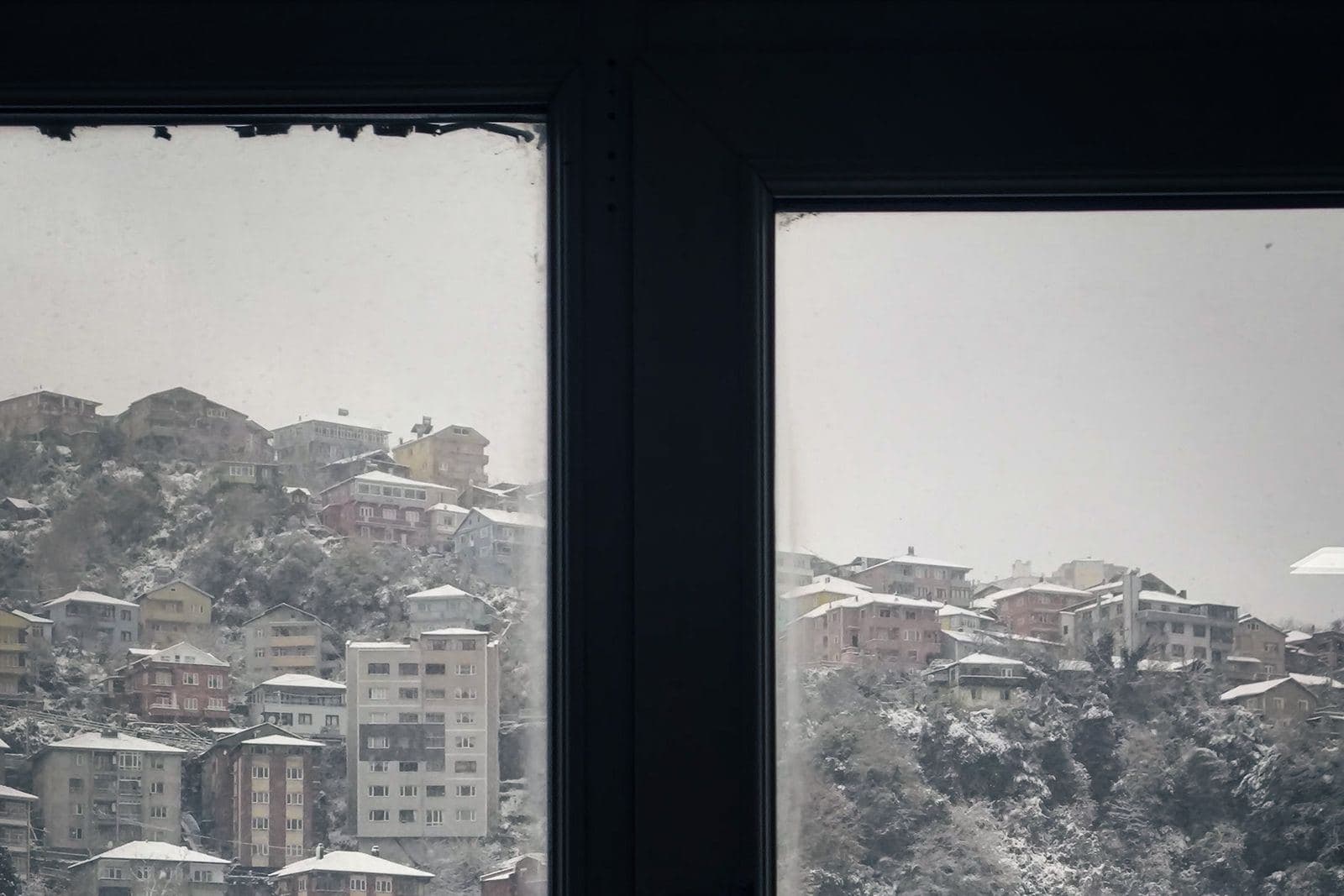 Blick durch ein Fenster auf eine verschneite Stadtlandschaft