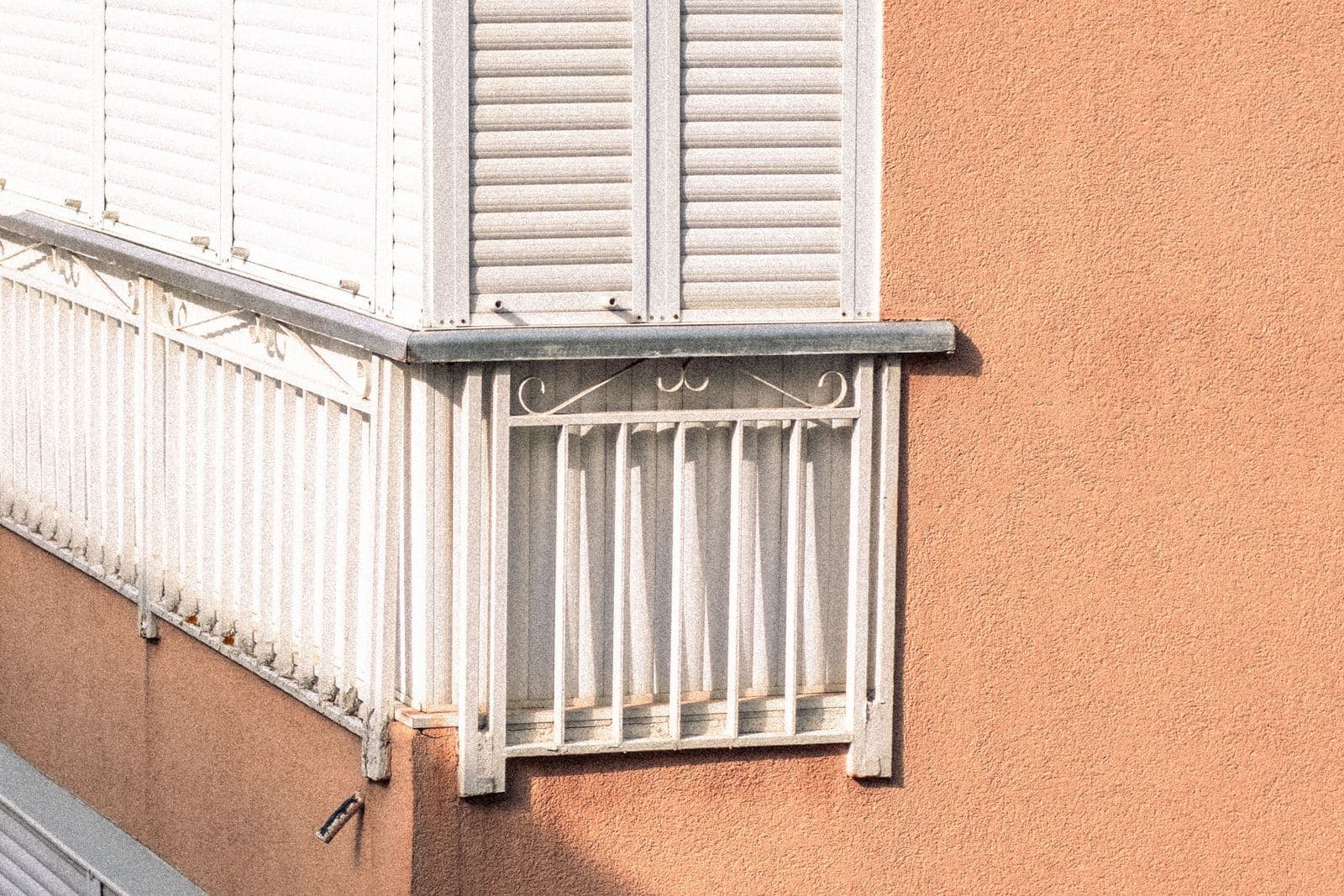 Fenster mit außen liegendem Vorbaurollladen an einer orangefarbenen Fassade