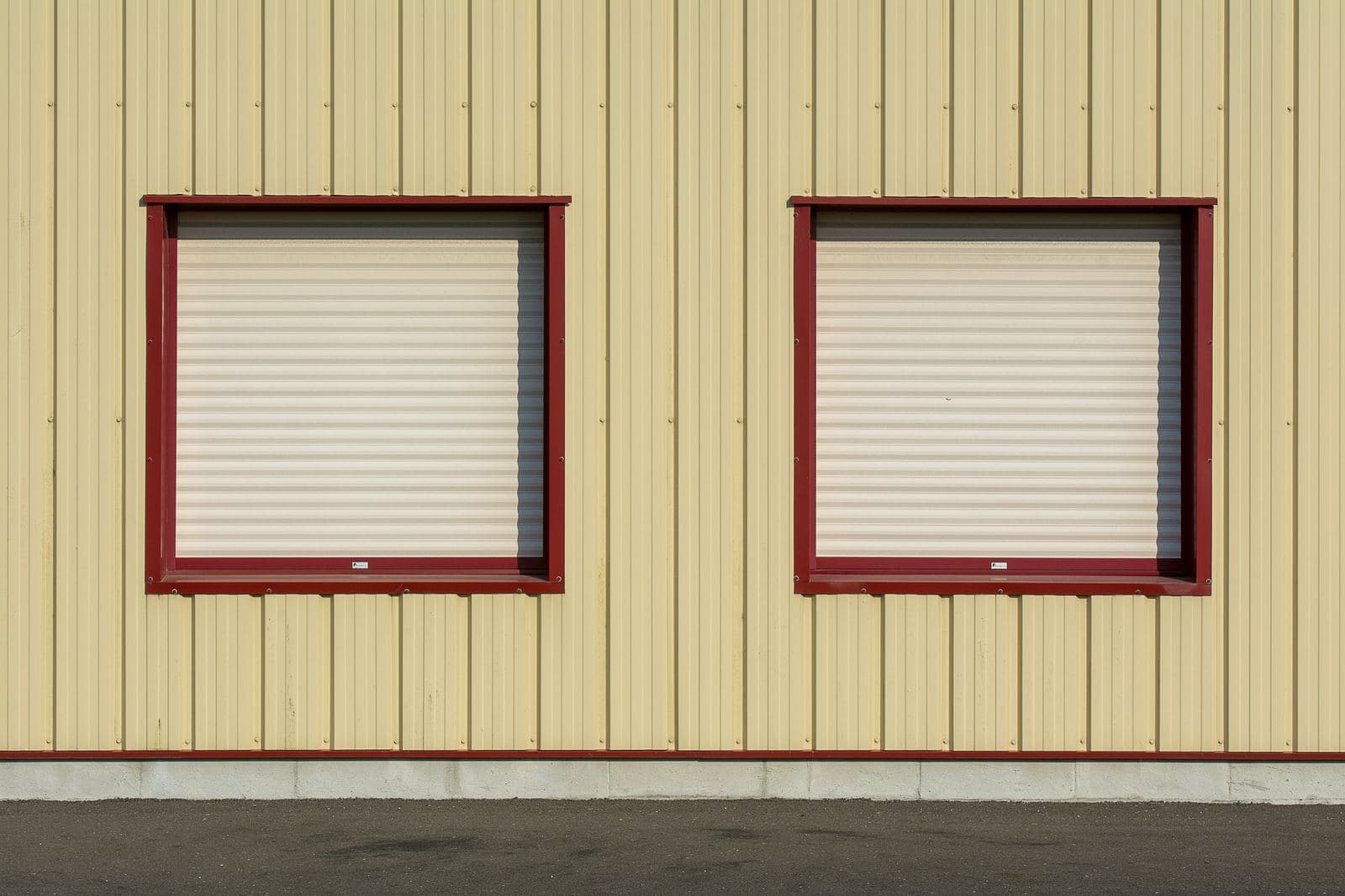 Zwei Fenster mit heruntergelassenen Rollläden an einer hellen Fassade