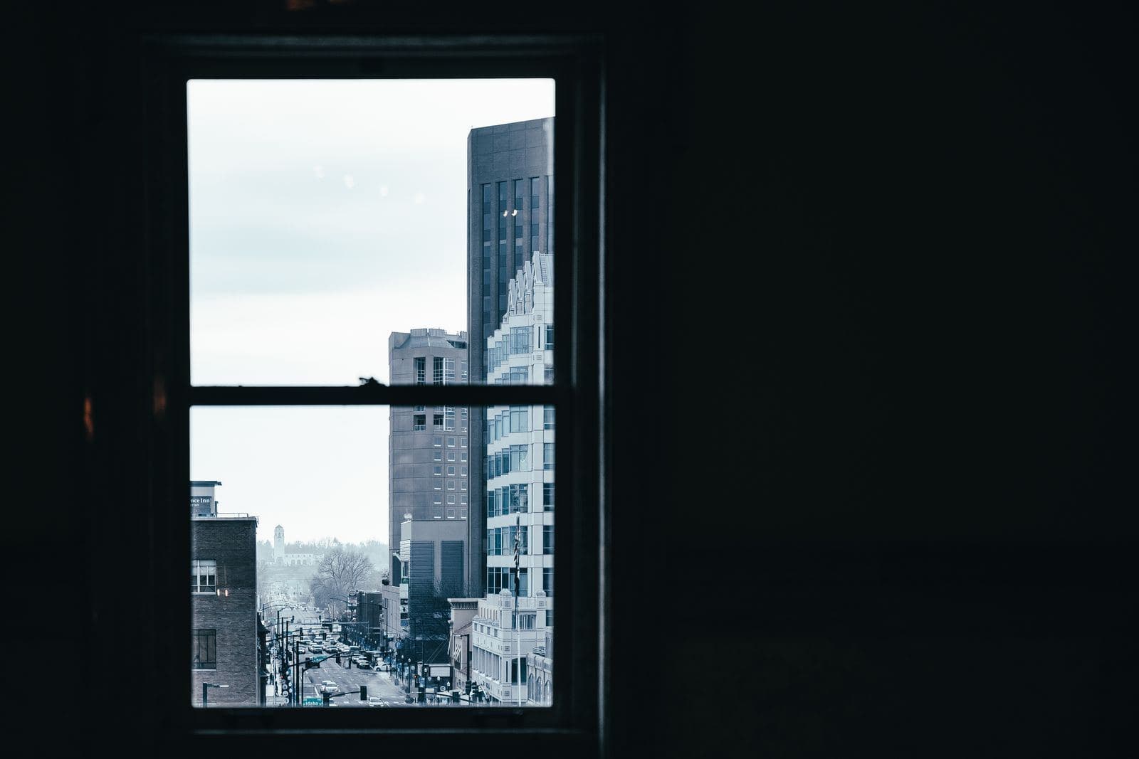Blick aus einem dunklen Raum durch ein Fenster auf eine Stadtstraße